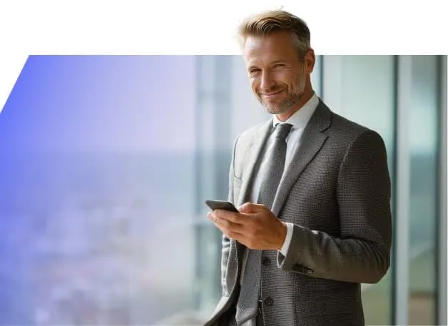 A trader smiling at his phone by an office window